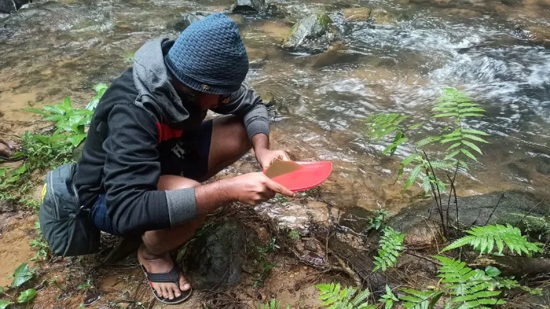 Researcher sampling for diatoms across a stream.